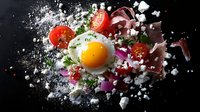 Dramatic food composition with sunny side up egg, fresh tomatoes, and scattered feta cheese against dark background, captured in explosive motion with flour splash.