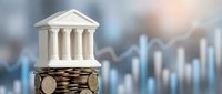 Miniature bank building model on stack of coins with financial chart background representing banking investment growth and economic stability concepts.