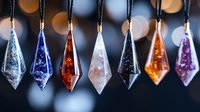 Colorful crystal pendants hanging in row with bokeh background, featuring blue, red, white and purple gemstones. Mystical jewelry display for spiritual decor.