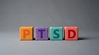 PTSD text on colorful wooden blocks arranged in a row against neutral background, used for mental health awareness, psychology education, and therapeutic counseling materials.