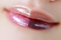 Sensual close up of glossy pink metallic lipstick on female lips with sparkle effect and soft focus background for beauty and cosmetic advertising.