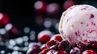 Creamy vanilla ice cream scoop with fresh cranberries and frozen berries on dark background, selective focus with bokeh lights creating festive mood.