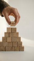 Male hand placing wooden block with TRUST text on pyramid of wooden cubes representing business foundation building and reliability concepts.