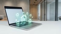 Modern laptop displaying smart home automation interface with connected device icons on office desk in contemporary workspace with glass walls.