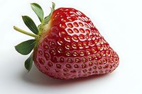 Fresh ripe strawberry with green leaves isolated on white background, showing detailed texture and natural pattern of seeds on bright red fruit surface.