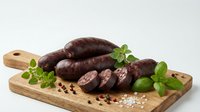 Fresh blood sausage slices on wooden cutting board with herbs and spices for gourmet cooking and traditional cuisine preparation.
