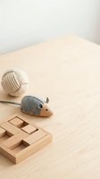 Wooden felt mouse toy, rope ball, and puzzle blocks arranged on a light wood surface, minimal Scandinavian style decor.