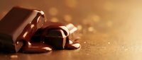 Melted dark chocolate pieces with glossy dripping sauce on golden surface creating luxurious dessert background for culinary and food photography projects.
