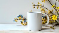 White ceramic coffee mug mockup with yellow and blue spring flowers on light background, styled product photography for branding and design presentation.