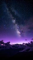 Spectacular meteor shower over Milky Way galaxy with purple twilight sky and dramatic clouds creating magical celestial scene for astronomy and space backgrounds.