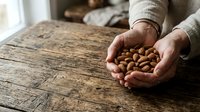 Hands holding roasted almonds on rustic wooden table, showcasing natural nuts for healthy snacking, cooking, and food photography.