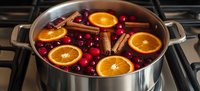 Mulled wine with orange slices, cranberries and cinnamon sticks simmering in steel pot on stove. Warm spiced holiday drink preparation for winter celebrations.