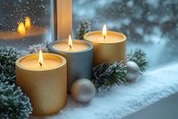 Three glowing candles on snowy windowsill with fir branches and silver ornaments create cozy winter atmosphere against frosty window background.
