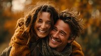 Happy couple laughing together in warm autumn light wearing cozy sweaters during golden hour outdoor portrait session for lifestyle photography.