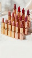 Collection of luxury lipsticks in golden tubes with various shades from nude to deep red arranged on marble surface for beauty and cosmetics branding.