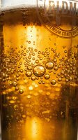 Craft beer glass filled with golden lager, showcasing carbonation bubbles and condensation droplets on exterior, premium beverage photography for advertising and hospitality design use.