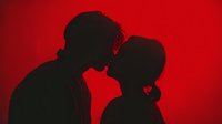 Romantic couple silhouettes touching foreheads on vibrant red background expressing love and intimacy for Valentine's Day greeting cards and wedding designs.