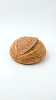 Artisan sourdough bread loaf with spiral scoring pattern isolated on white background for bakery and food design projects.