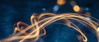 Golden light trails creating flowing curves and loops against dark blue textured background with bokeh effects for modern digital design projects.