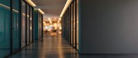 Modern office corridor with glass walls and warm lighting creating professional corporate atmosphere for business presentations.