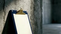 Blue clipboard with blank white paper and golden clip leaning against concrete wall in urban setting for business documentation and note-taking.