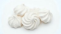 Fluffy white meringue cookies with swirled peaks isolated on white background, ready for bakery, dessert, and confectionery design projects.