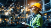 Female engineer in yellow hard hat and safety vest analyzing data with futuristic holographic interface in industrial facility at night.