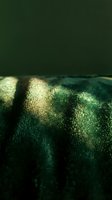 Close-up of emerald green fabric with gold metallic stripes catching light, showcasing luxurious textile texture for fashion, interior design, and upholstery projects.