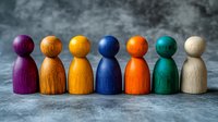 Colorful wooden pawns standing in row symbolizing diversity, teamwork and inclusion. Group of multicolored figures represents unity and cooperation in business.