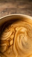 Closeup of freshly brewed espresso with rich crema and swirling foam patterns in ceramic cup, suitable for coffee shop menus, beverage advertising, and café branding materials.