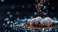 Homemade chocolate truffles dusted with coconut flakes on dark plate against black background with sprinkled sugar and bokeh light effect.