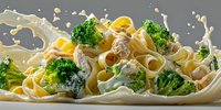 Creamy fettuccine pasta with broccoli florets and chicken in white sauce, dynamic food splash effect on gray background.