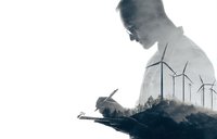 Double exposure silhouette of man writing in notebook with wind turbines, symbolizing renewable energy planning and sustainable development.