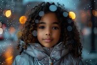 Young African American girl with natural curly hair wearing silver winter jacket against blurred bokeh lights and snowfall background, expressing innocent smile.