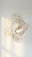 Blonde hair strands swirling in dynamic motion against soft beige background creating abstract flowing pattern for beauty and haircare concepts.
