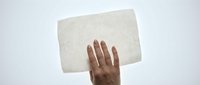 Hand holding blank white paper sheet against light background for presentation mockup and design template use.