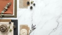 Flat lay workspace with natural materials, dried flowers, notebooks and candles on marble background for creative projects and planning.