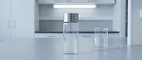 Clear glass vials with silver caps on laboratory counter in modern sterile research facility for pharmaceutical testing and scientific experiments.