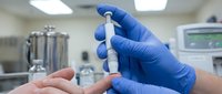 Medical professional in blue gloves preparing syringe injection in sterile laboratory environment for healthcare treatment and pharmaceutical research.