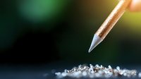 Macro shot of pencil tip hovering over scattered diamond dust and crystals against dark background with bokeh effect, luxury creative concept for jewelry design and art.