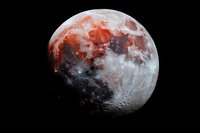Dramatic red and gray moon phases against black background showing detailed lunar surface with craters and shadows in high resolution astronomical photography.