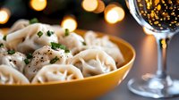 Fresh homemade pasta with herbs in yellow bowl alongside sparkling wine glass with warm bokeh lights creating elegant dining atmosphere for celebrations.