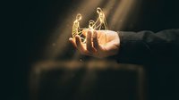 Business professional holding glowing lightbulb with golden light rays symbolizing innovation, creativity and bright ideas for corporate success.