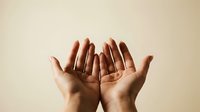 Open hands cupped together in prayer or receiving gesture against neutral beige background for spiritual and wellness concepts.