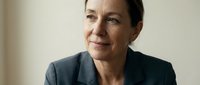 Professional middle-aged Caucasian businesswoman in dark suit smiling confidently in modern office setting for corporate leadership and success concepts.