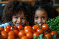 Two cheerful African American children with curly natural hair smiling behind fresh red tomatoes and green herbs, representing healthy eating and natural food lifestyle.