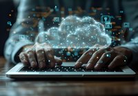 African American hands typing on laptop keyboard with glowing cloud computing visualization and digital icons floating above, representing modern technology solutions.