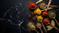 Colorful spices and herbs in wooden spoons on dark marble background. Cooking ingredients including turmeric, paprika, cumin for culinary recipes and seasoning.