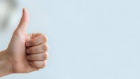 Hand showing thumbs up gesture on white background expressing approval, success and positive feedback for business presentations.