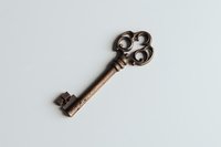 Vintage ornate bronze skeleton key with decorative bow design isolated on light gray background, suitable for antique collections and decorative elements.